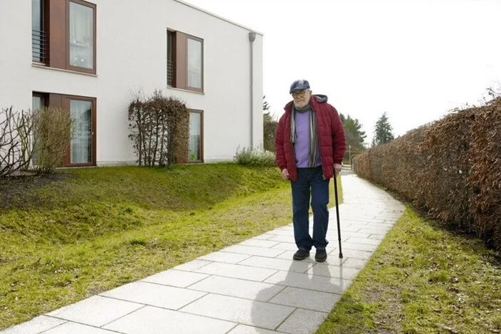 Ein Mann geht mit Gehstock spazieren.