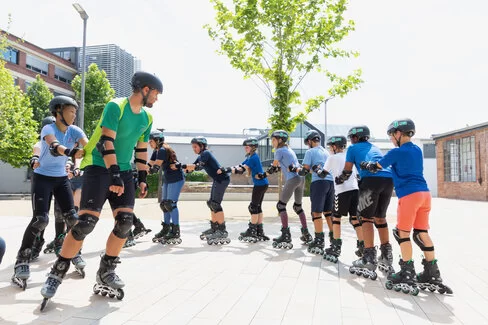 Eine Menschengruppe fährt auf Inlineskates in einer Schlange auf einem Gebäudehof.