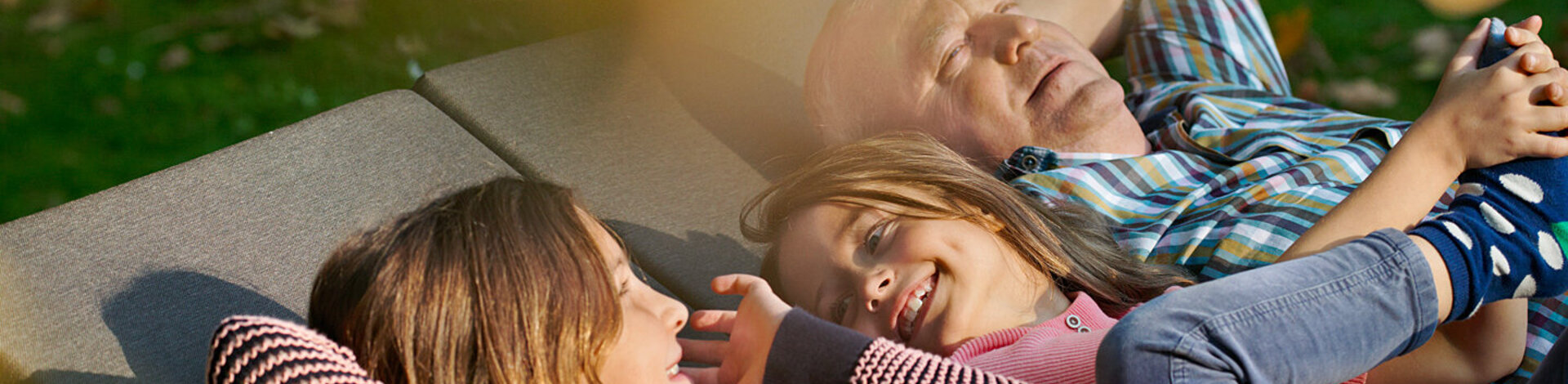 Zwei Kinder und ein älterer Mann liegen in der Sonne. Mit dem Familiencoach Krebs können sie gemeinsam besser mit der Krebserkrankung umgehen.