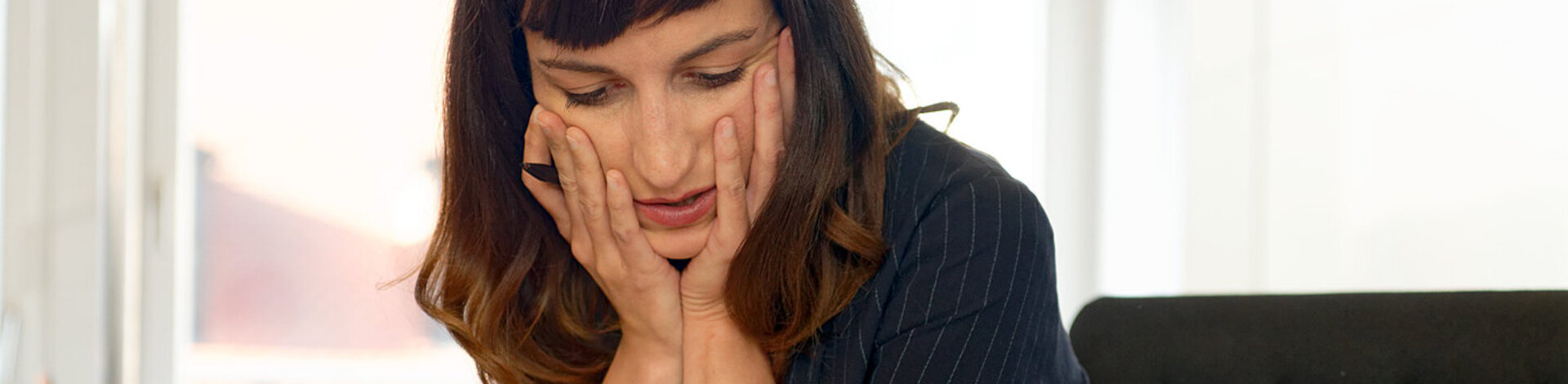 Eine gestresst wirkende Frau denkt nach. Die AOK bietet das Programm „Stress im Griff“ und Kurse zur Entspannung an.