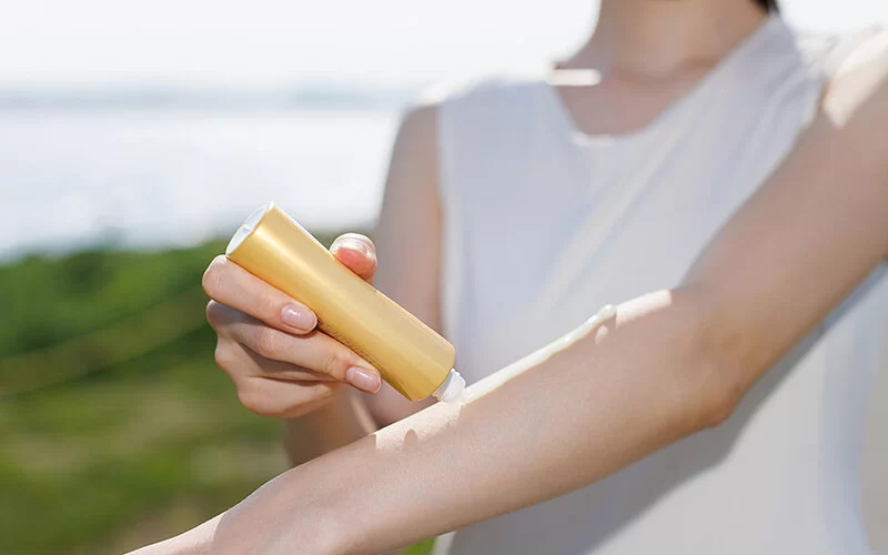 Eine Frau trägt Sonnenschutzmittel auf ihrem Unterarm auf.