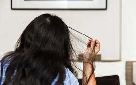 Eine Frau, die unter Trichotillomanie leidet, ist kurz davor, sich einige Haare vom Kopf auszureißen.