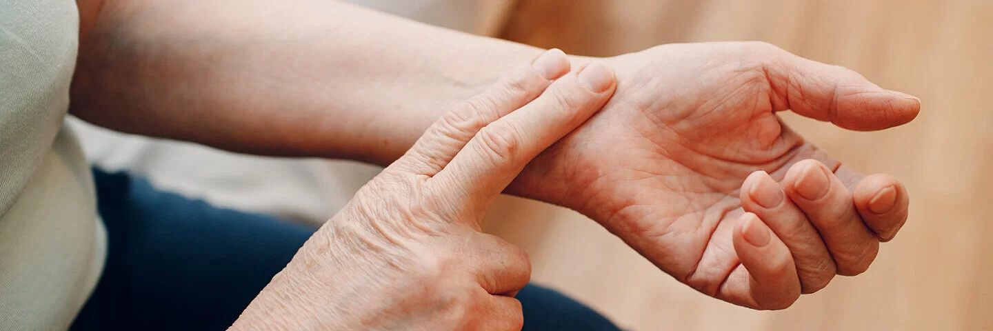 Frau misst mit zwei Fingern ihren Puls am Handgelenk.