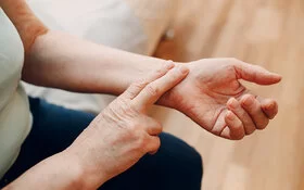 Frau misst mit zwei Fingern ihren Puls am Handgelenk.