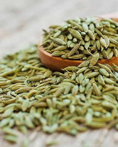 Anissamen liegen auf einem Holzlöffel und auf einem Tisch.