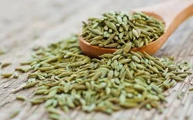 Anissamen liegen auf einem Holzlöffel und auf einem Tisch.