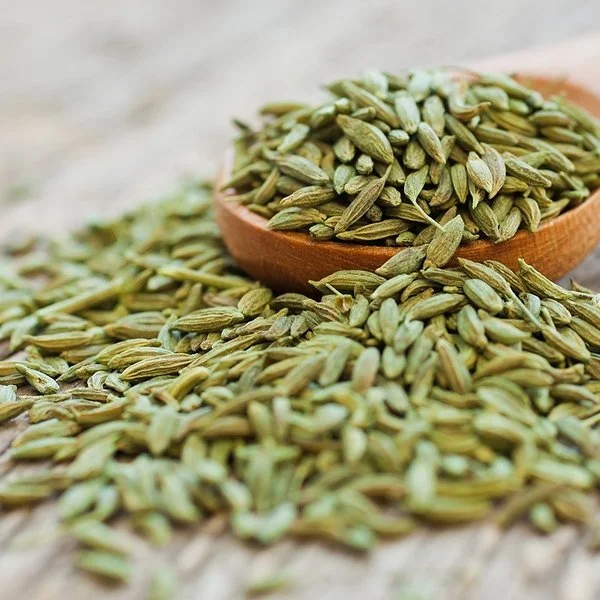 Anissamen liegen auf einem Holzlöffel und auf einem Tisch.