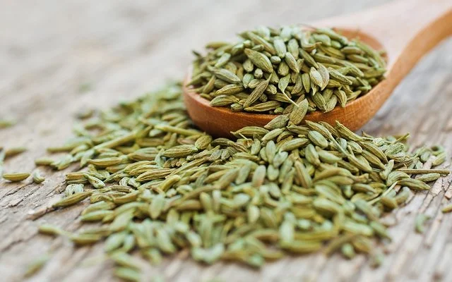Anissamen liegen auf einem Holzlöffel und auf einem Tisch.