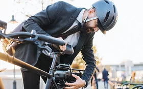 Mann mit Helm prüft vor dem Fahrradfahren, ob sein Rad verkehrstauglich ist.