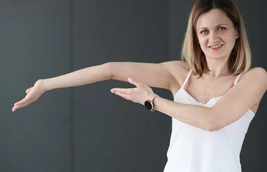 Eine junge Frau zeigt auf ihren überstreckten Arm.