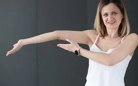 Eine junge Frau zeigt auf ihren überstreckten Arm.