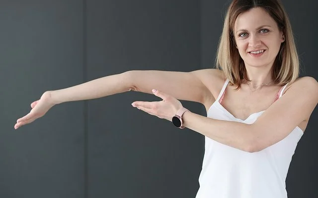 Eine junge Frau zeigt auf ihren überstreckten Arm.