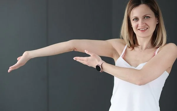 Eine junge Frau zeigt auf ihren überstreckten Arm.