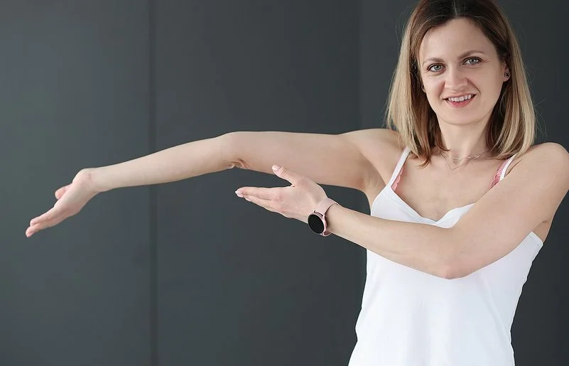 Eine junge Frau zeigt auf ihren überstreckten Arm.