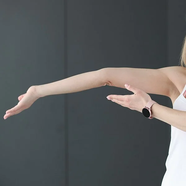 Eine junge Frau zeigt auf ihren überstreckten Arm.