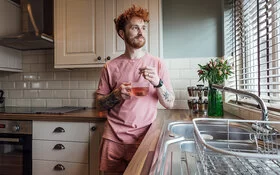 Ein Mann steht in seiner Küche und trinkt Tee.