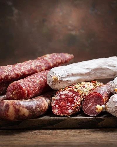 Verschiedene Sorten von Salami, die auf einem Holzbrett liegen.