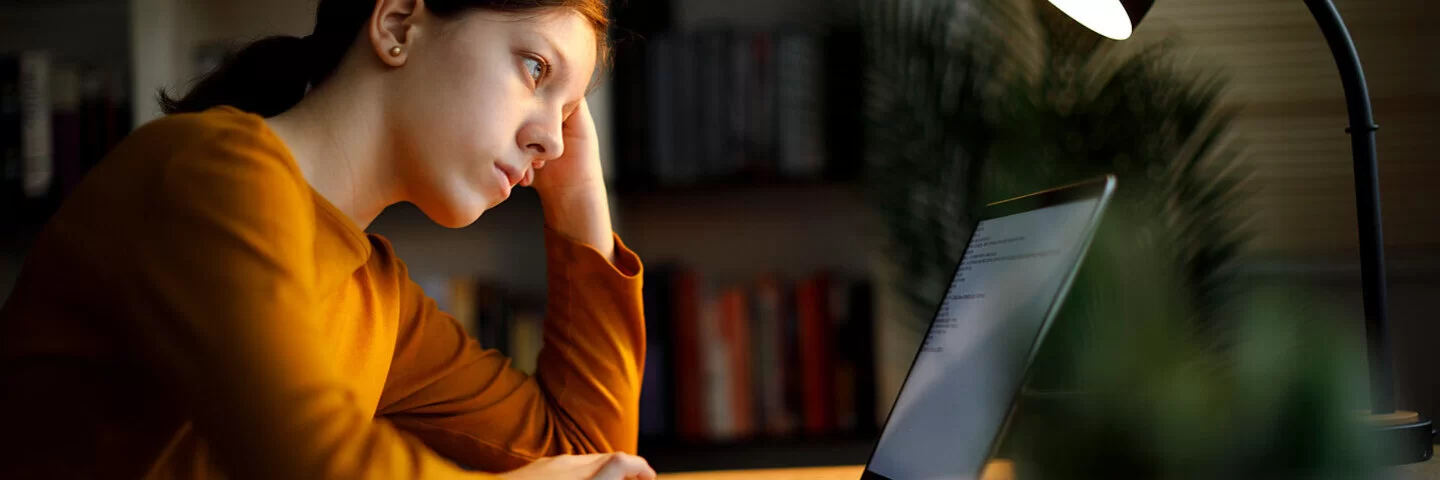 Junge, leicht depressive Frau macht Online-Therapie moodgym am Laptop.