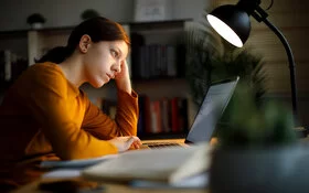 Junge, leicht depressive Frau macht Online-Therapie moodgym am Laptop.