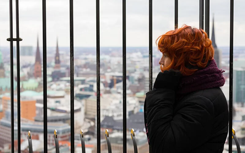 Frau mit Höhenangst steht auf Aussichtsplattform, um die Angst zu besiegen.