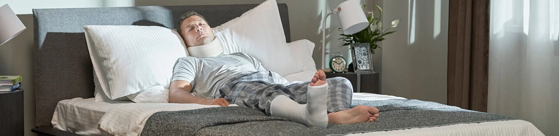 Ein Mann mit Gips am Bein liegt im Bett. Die AOK zahlt Versicherten Krankengeld.
