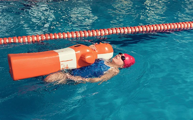 Ein Mädchen trainiert im Schwimmbad die Rettungssituation mit einer Übungspuppe.