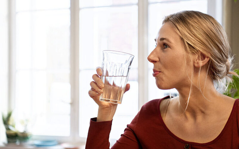 Frau will ihre Konzentration steigern, indem sie ein Glas Wasser trinkt.