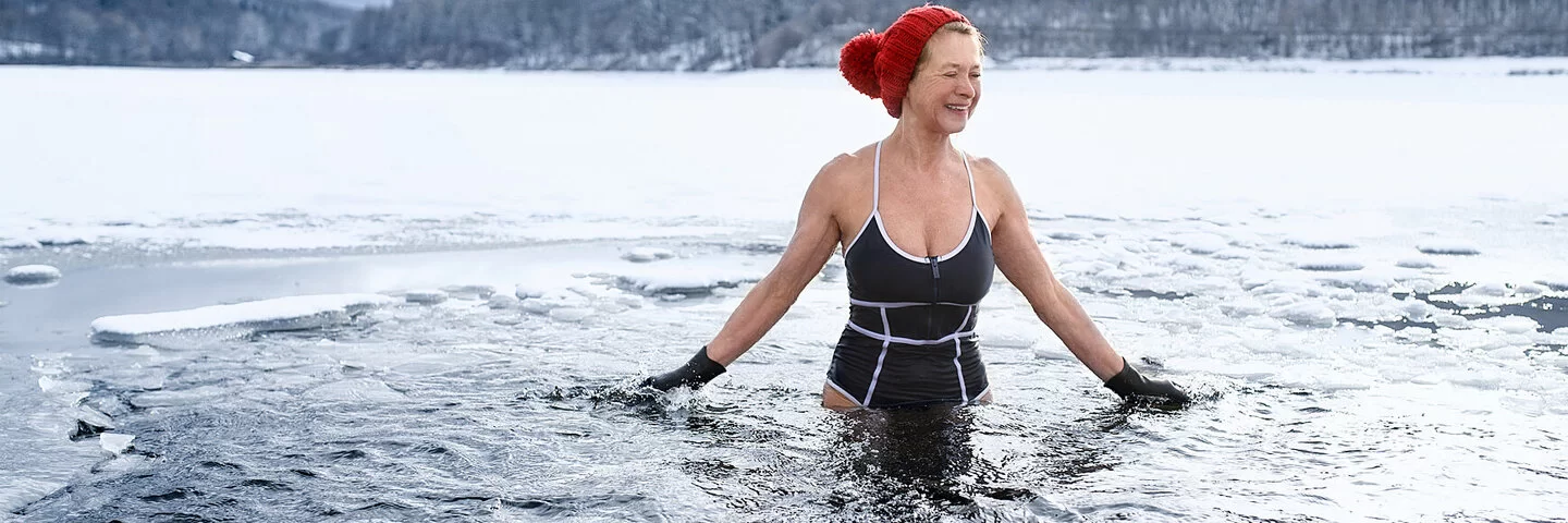 Frau mit Mütze geht Eisbaden.