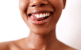 Eine junge Frau streicht mit der Zunge über ihre Zähne.