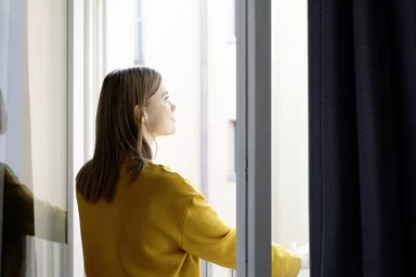 Eine Frau schaut aus einem offenen Fenster.