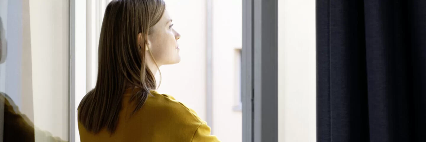 Eine Frau schaut aus einem offenen Fenster.