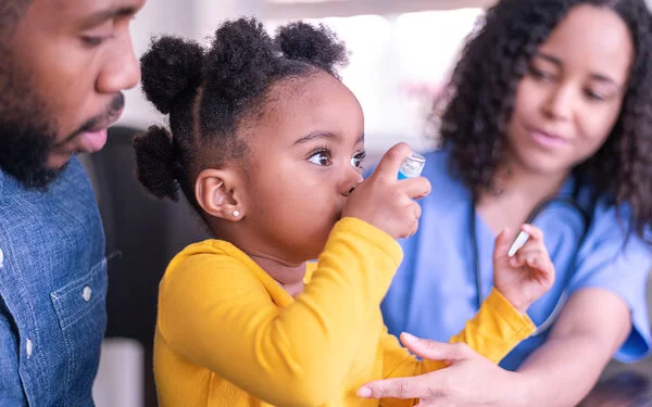 Ein Kind mit Asthma testet in einer Arztpraxis einen Inhalator.