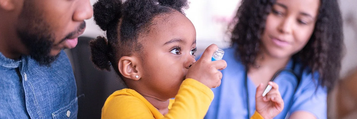 Ein Kind mit Asthma testet in einer Arztpraxis einen Inhalator.