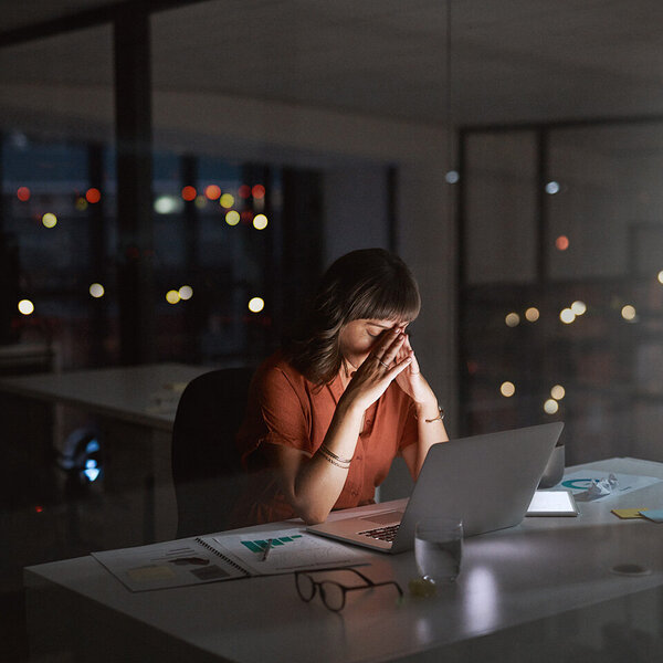 Frau arbeitet gestresst bis tief in die Nacht im leeren Büro.
