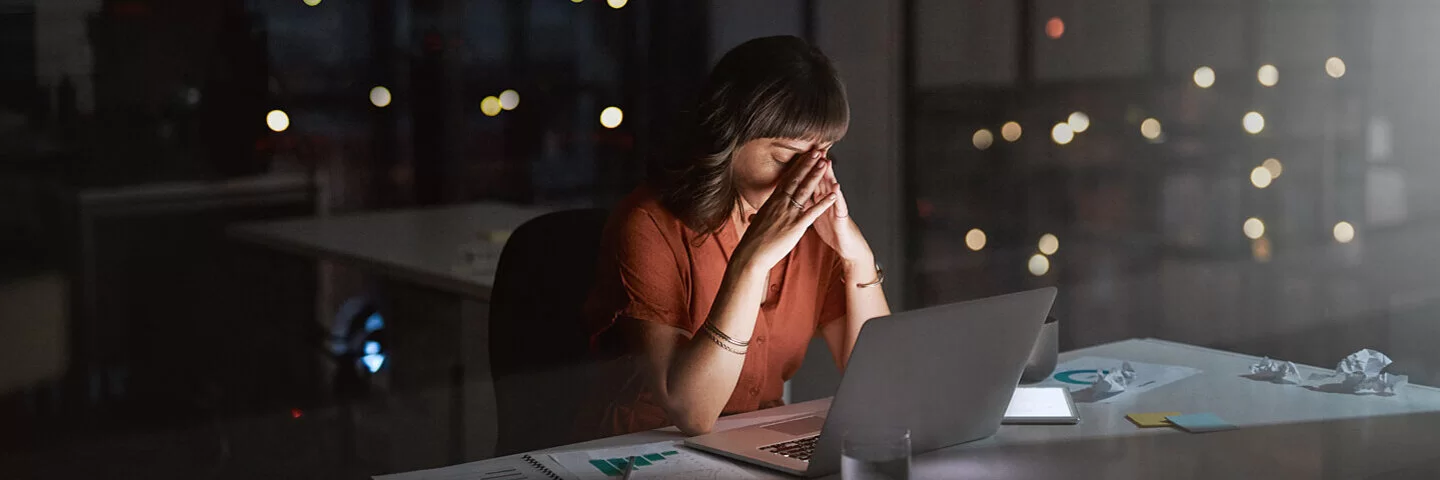 Frau arbeitet gestresst bis tief in die Nacht im leeren Büro.