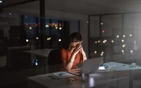 Frau arbeitet gestresst bis tief in die Nacht im leeren Büro.