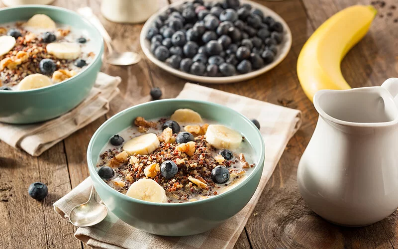 Eine Schale mit Quinoa und Obst als gesundes Frühstück, denn ballaststoffreiche Lebensmittel unterstützen die Verdauung.