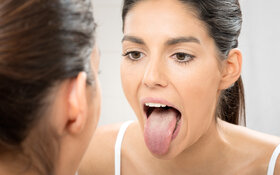 Frau checkt belegte Zunge im Spiegel