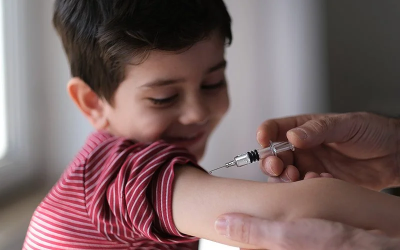 Ein Junge streckt den Arm aus, um eine Impfung gegen Masern zu bekommen.