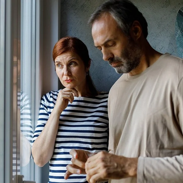 Eine Frau und ein Mann stehen nachdenklich vor einem Fenster.