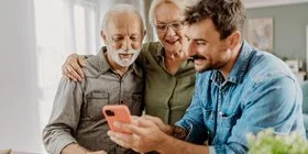 Mann zeigt Eltern Pflege-App am Smartphone