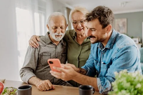 Mann zeigt Eltern Pflege-App am Smartphone