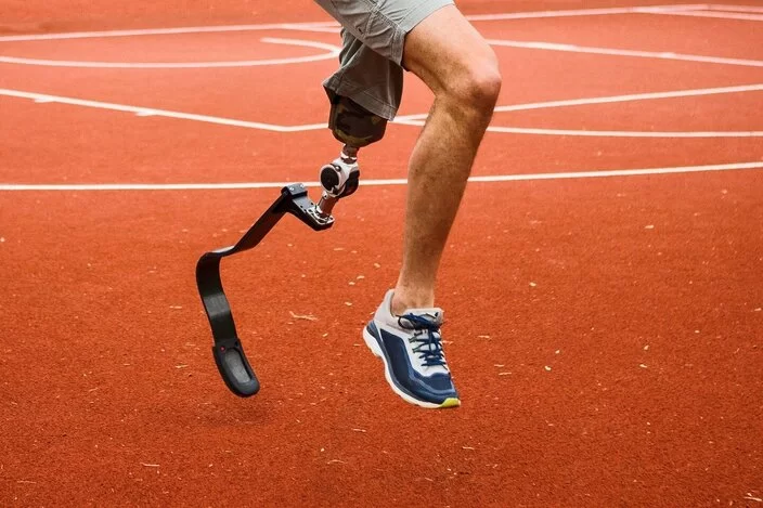 Ein junger Mann auf dem Sportplatz mit Beinprothese