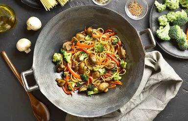 Wokpfanne mit Brokkoli, Pilzen, Paprika und Nudeln aus der Vogelperspektive.