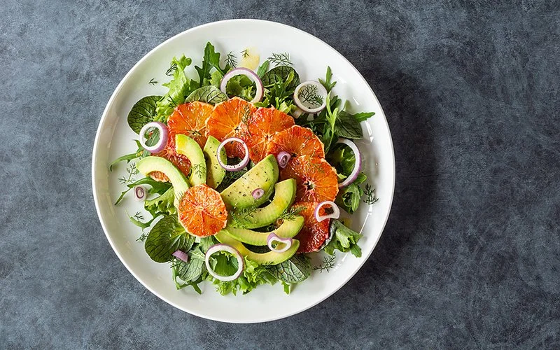 Ein Salatteller mit Orangen, Avocado und Zwiebeln.