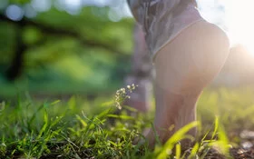 Die nackten Füße einer Frau in Jeans beim Barfußgehen über eine Wiese.