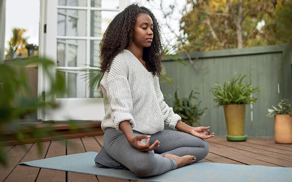 Frau meditiert im Freien, ihre Entspannungstechnik gegen chronische Schmerzen.