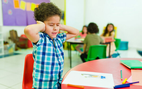 Ein hochsensibles Kind hält sich im Kindergarten die Ohren zu.
