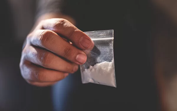 Eine Hand hält ein Beutelchen mit weißem Pulver.