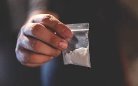 Eine Hand hält ein Beutelchen mit weißem Pulver.